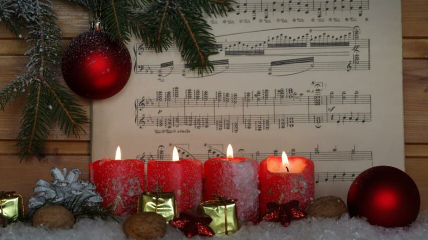 Brennende Kerzen und ein Notenblatt eines Weihnachtsliedes Brennende Kerzen und ein Notenblatt eines Weihnachtsliedes