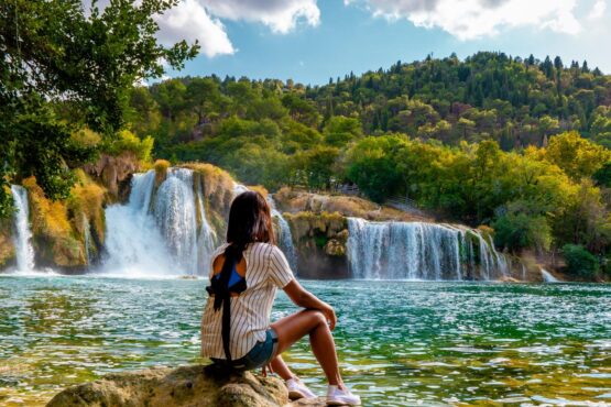 Frau vor einem Wasserfall im Nationalpark Krka, Kroatien