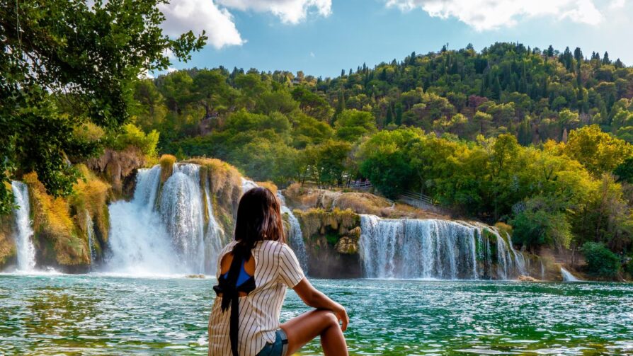 Frau vor einem Wasserfall im Nationalpark Krka, Kroatien