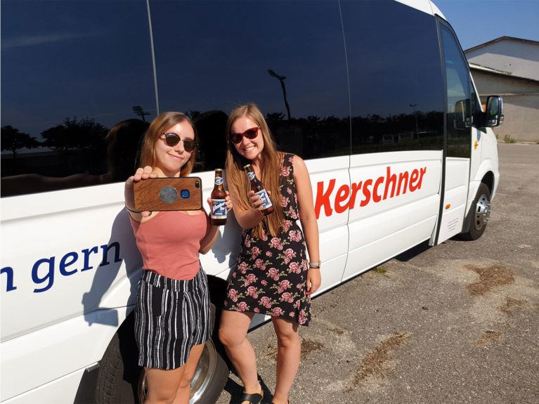 Zwei Mädels mit Wieselburger Bier vor Kerschner-Bus, die ein Selfie machen