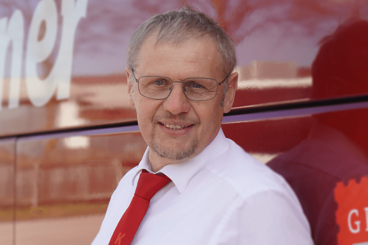 Gottfried Poehacker, Reisebusfahrer bei Kerschner Reisen, steht vor einem roten Reisebus