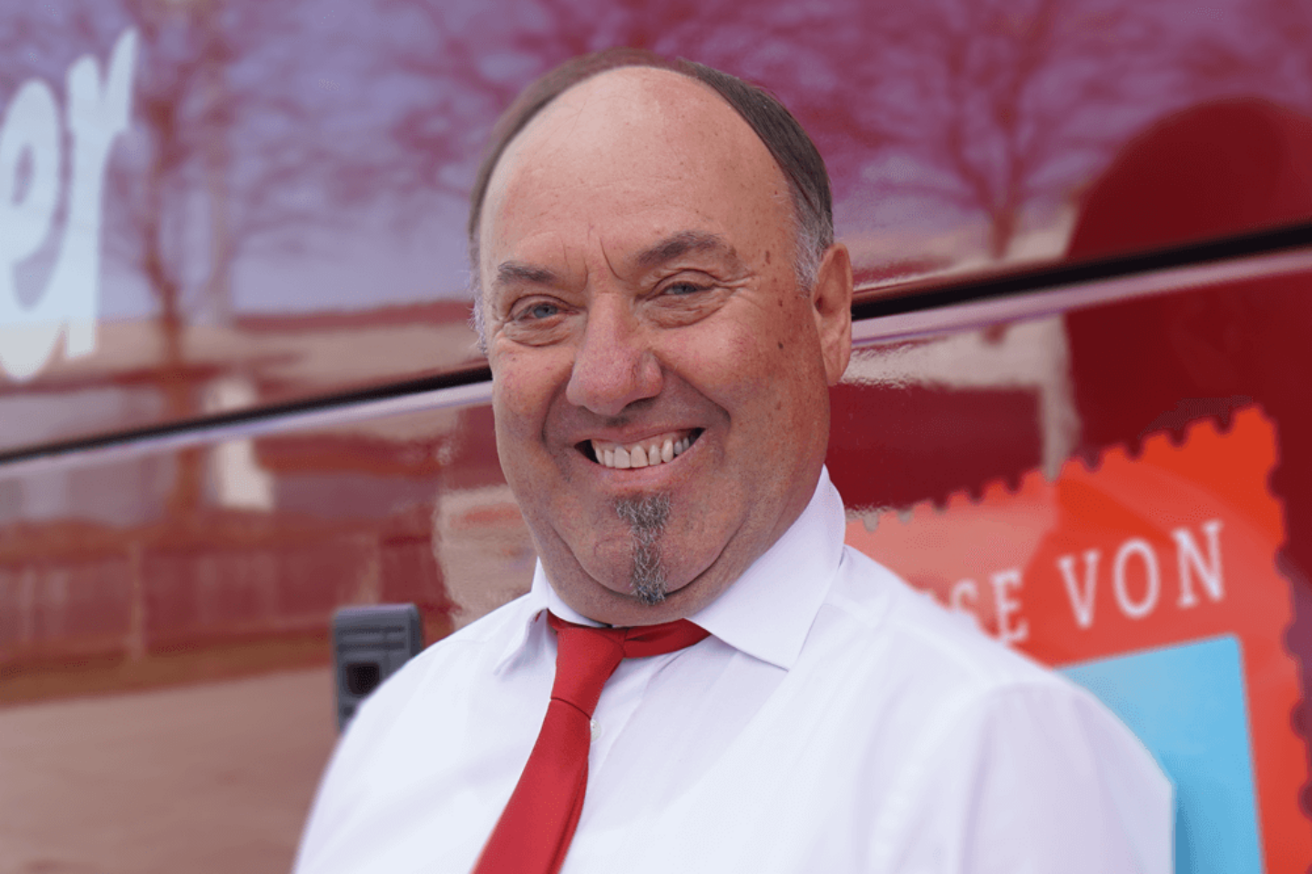 Josef Herbeck, Reisebusfahrer bei Kerschner Reisen, steht vor einem roten Reisebus