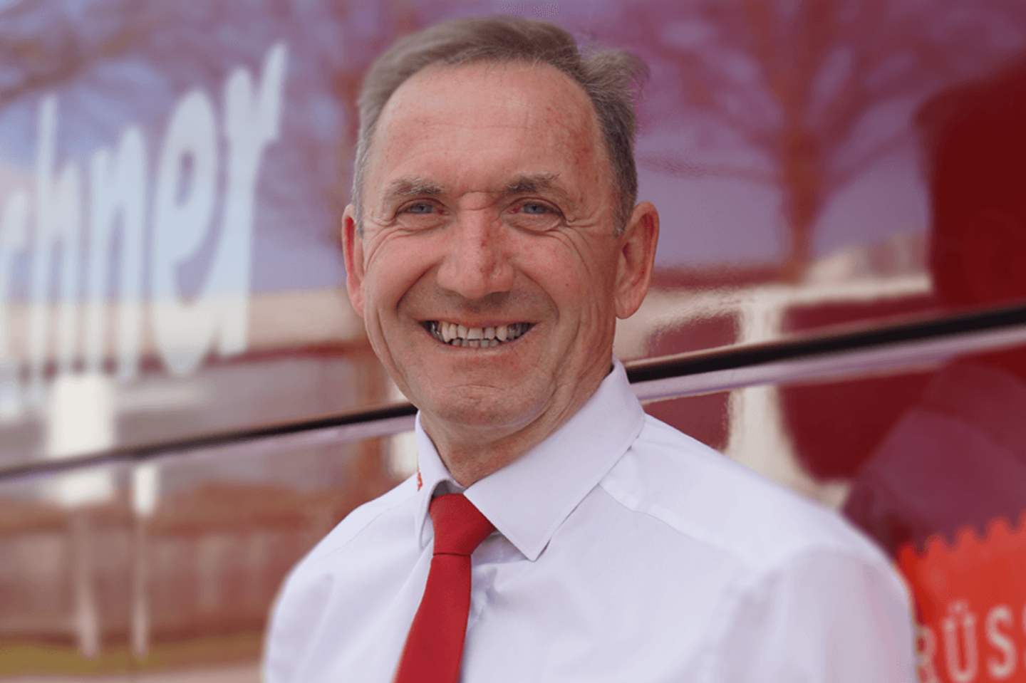 Josef Schaumberger, Reisebusfahrer bei Kerschner Reisen, steht vor einem roten Reisebus